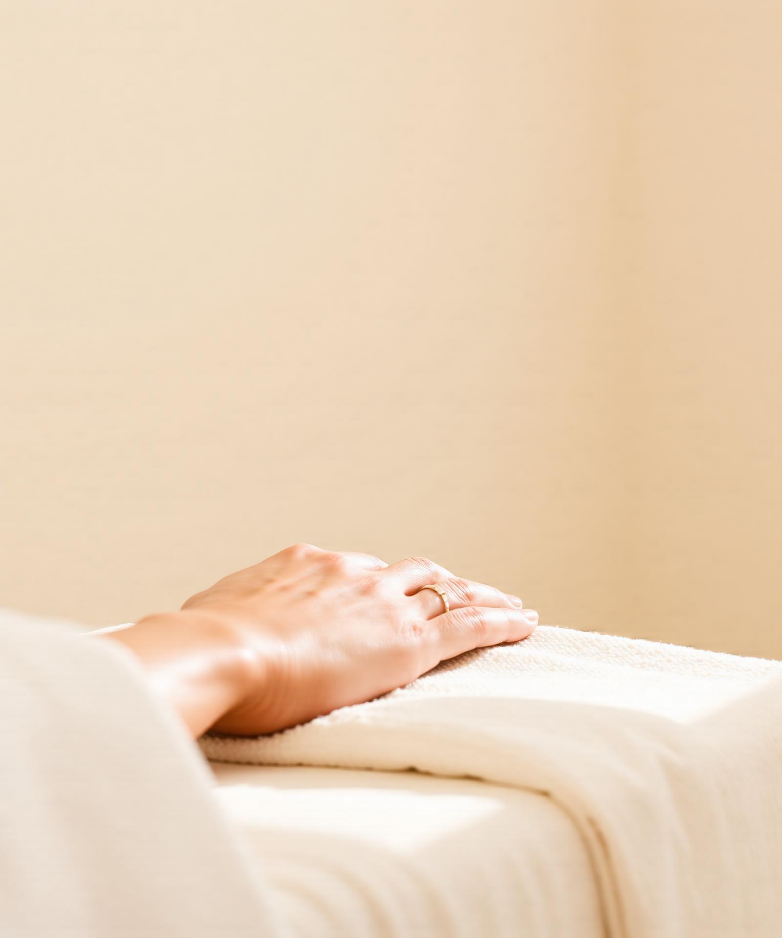 Hands resting on a soft spa towel in warm natural light